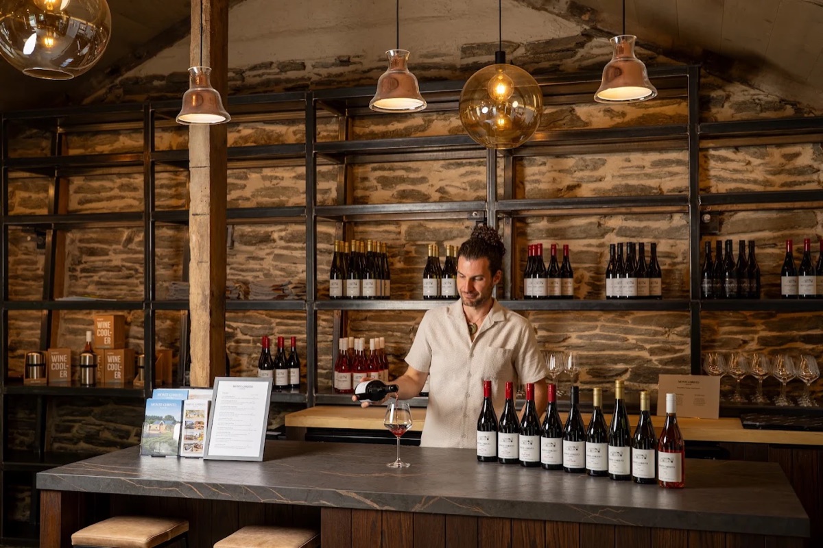 Pouring pinot at the Monte Christo cellar door bar inside the historic Gibbston Hotel stone stables