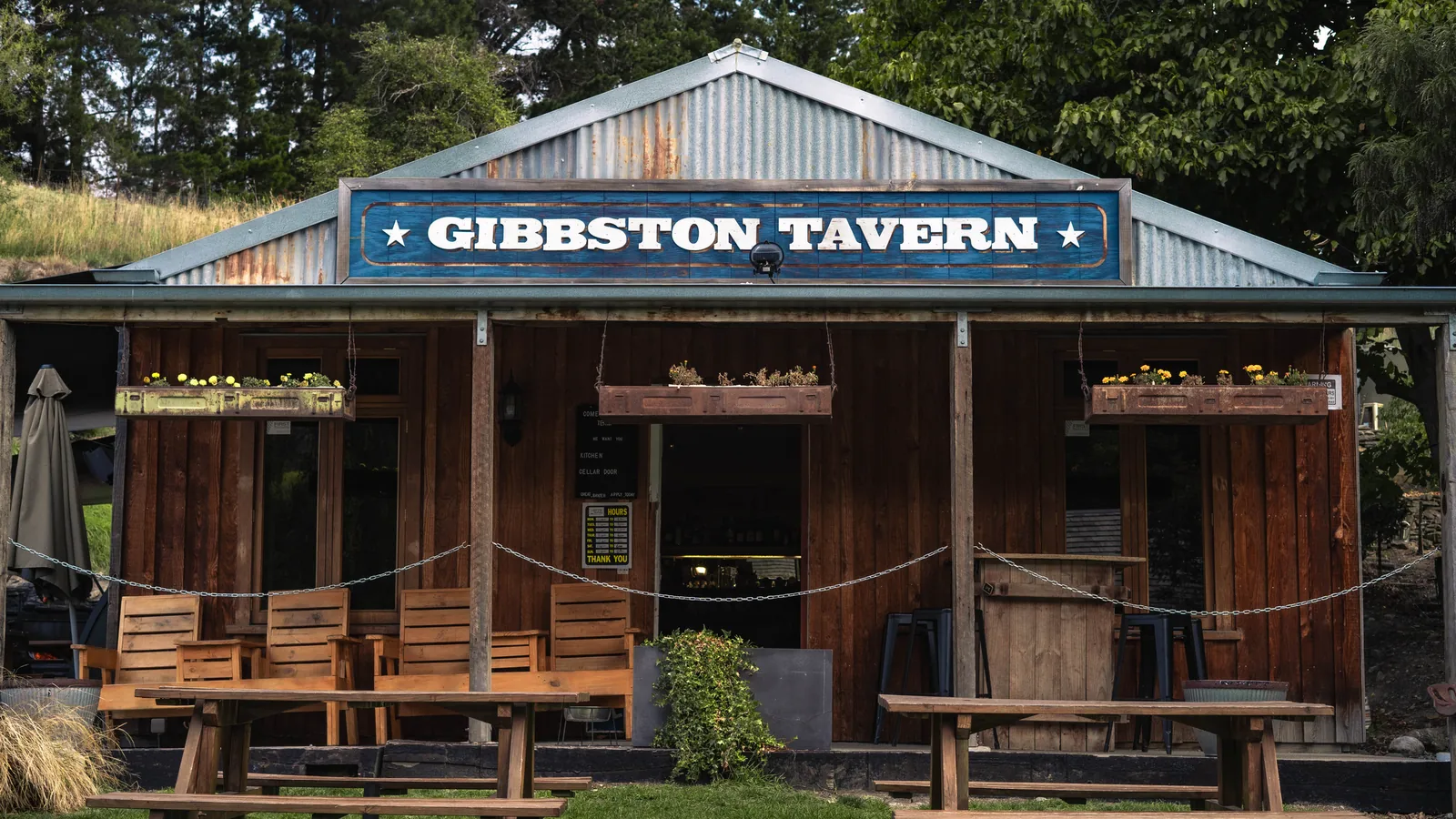 The tavern's veranda and painted sign across a row of picnic tables on the front lawn
