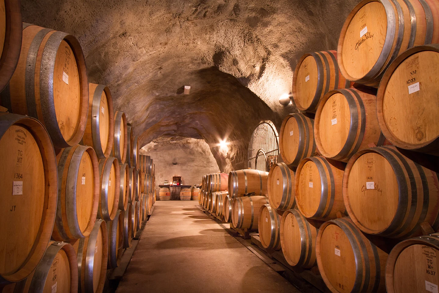 Oak barrels stacked head-high either side of the tunnel through Gibbston Valley's wine cave, cut straight into the schist hillside